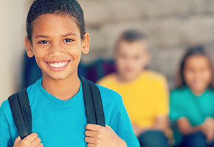 Picture of a 10 year old with a backpack smiling at the camera
